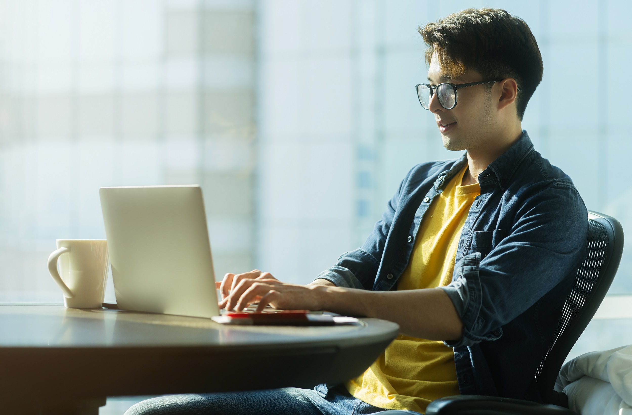 A man sitting at a table and working on a laptop