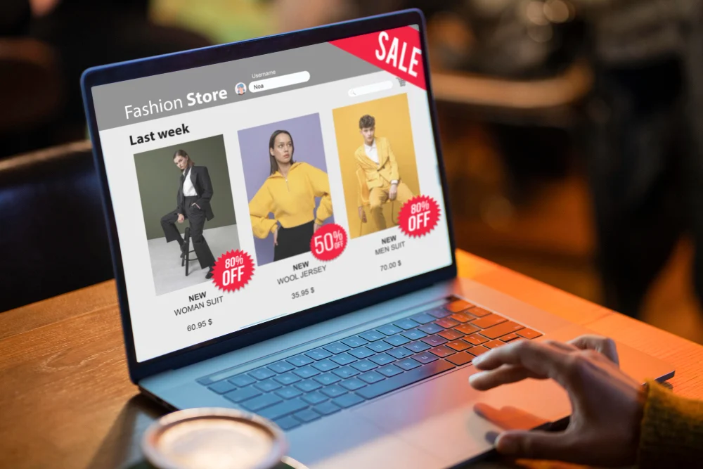 Why are My Google Shopping Ads Getting Clicks But No Sales? 1 A modern, dark-gray laptop displaying a mockup of a minimalist e-commerce fashion website with a "Sale" banner